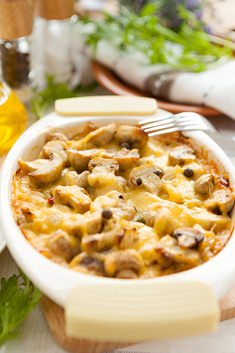 A creamy mushroom casserole topped with melted cheese, served in a ceramic dish.