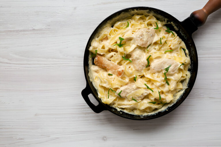 Creamy fettuccine pasta with chicken in a black skillet