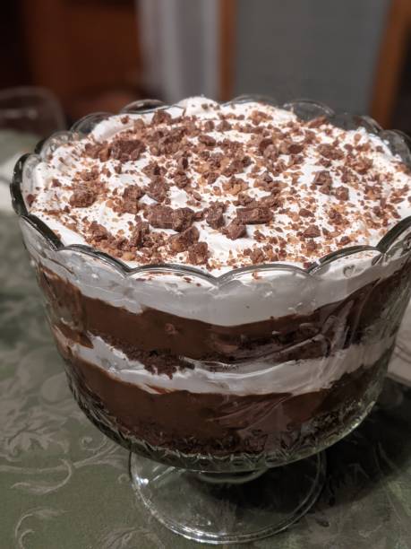 A decorative glass bowl filled with layers of chocolate mousse, whipped cream, and topped with chocolate shavings.