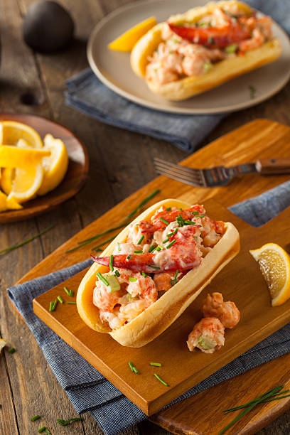 A delicious lobster roll with shrimp served on a wooden cutting board, garnished with chives and lemon.