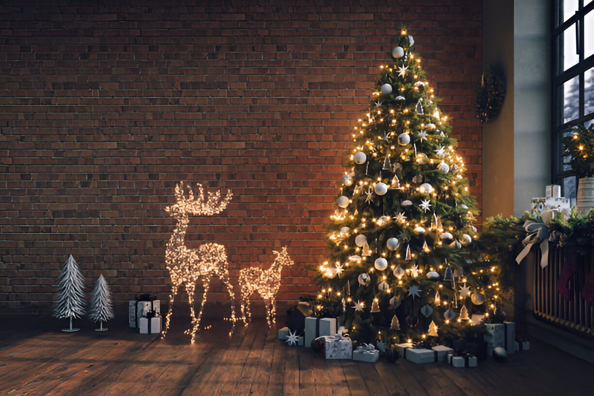 A beautifully decorated Christmas tree next to illuminated deer figures in a cozy interior setting.