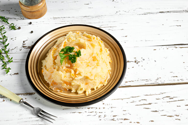 A serving of mashed potatoes garnished with parsley on a brown plate surrounded by herbs and a fork