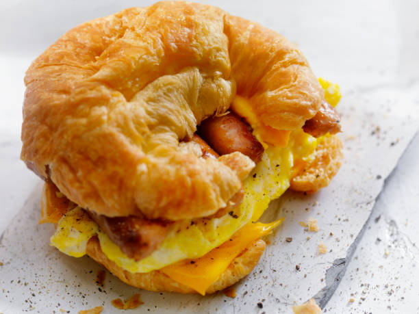 A croissant sandwich filled with scrambled eggs, cheese, and sausage