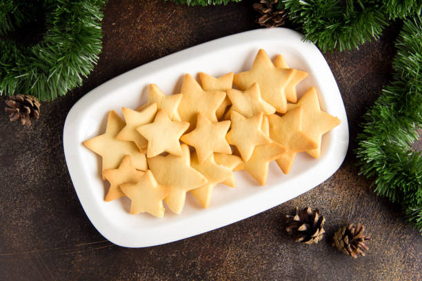 A platter of star-shaped cookies on a rustic table with pinecones and greenery