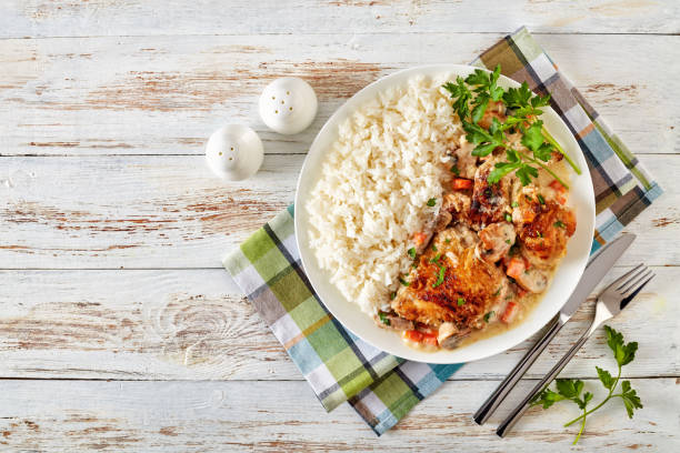 A plate of grilled chicken served with white rice and garnished with parsley on a checkered napkin.