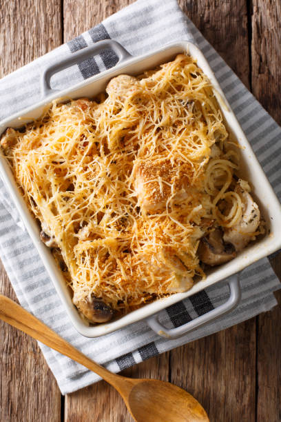 A baked pasta dish topped with golden brown cheese and mushrooms in a white casserole dish