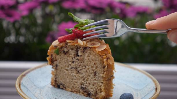 A slice of cake topped with strawberries and mint, served on a blue plate with a fork.