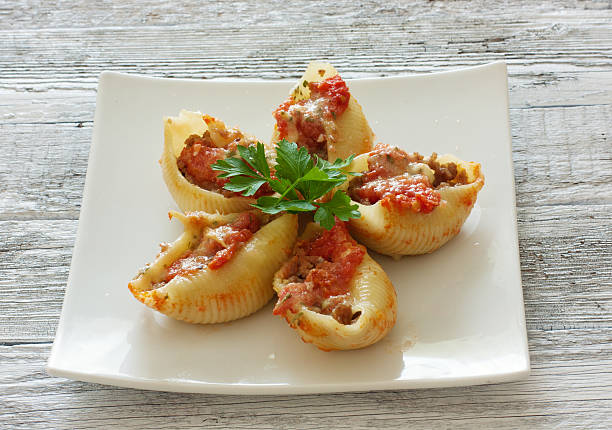 A plate of stuffed pasta shells filled with meat and topped with sauce and parsley.