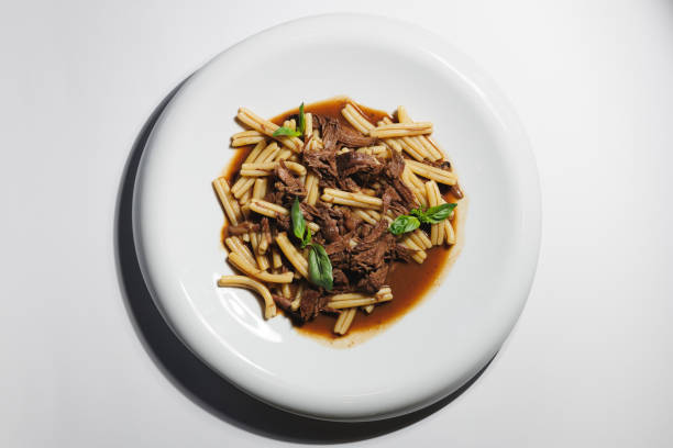 A delicious plate of pasta with shredded beef and garnished with basil leaves.