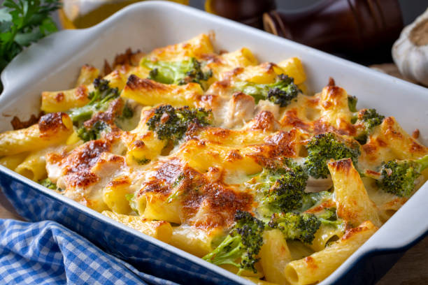 A baked pasta dish with broccoli, topped with melted cheese, served in a white casserole dish.