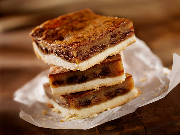 Three layers of delicious dessert bars with a glossy top, sitting on crinkled parchment paper.