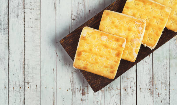 A wooden platter with square crackers on a rustic wooden background