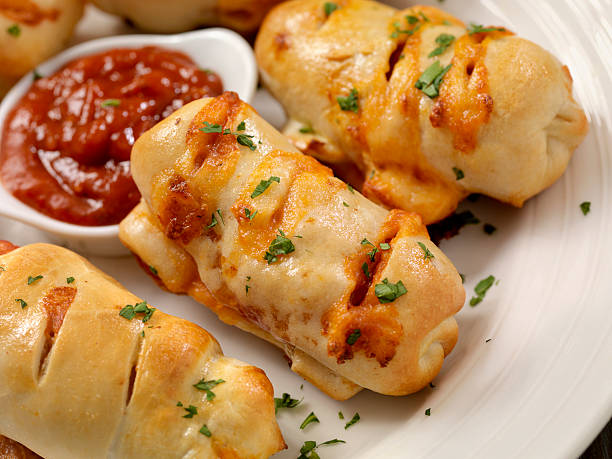 Baked cheesy roll-ups on a white plate with marinara sauce