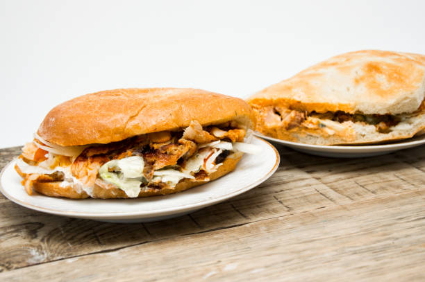 Two delicious sandwiches filled with grilled chicken, lettuce, and sauce, served on plates on a wooden table.