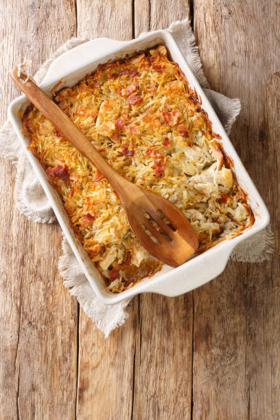 Baked casserole with shredded chicken and a golden crust in a white dish, served with a wooden spoon.