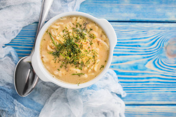 A bowl of creamy soup garnished with fresh herbs on a blue wooden background