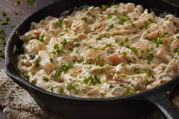 A creamy chicken dish with herbs and vegetables in a cast iron skillet.