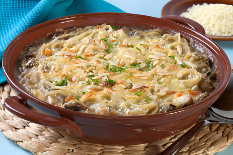 A delicious dish of baked pasta with mushrooms, covered in melted cheese and garnished with sliced almonds and herbs