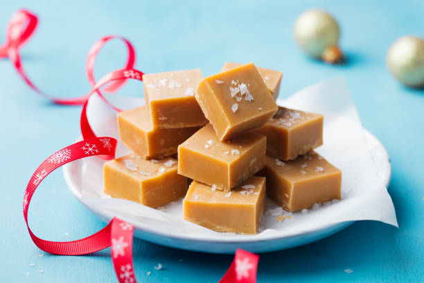 A plate of caramel fudge squares topped with sea salt, surrounded by festive ribbons and ornaments.