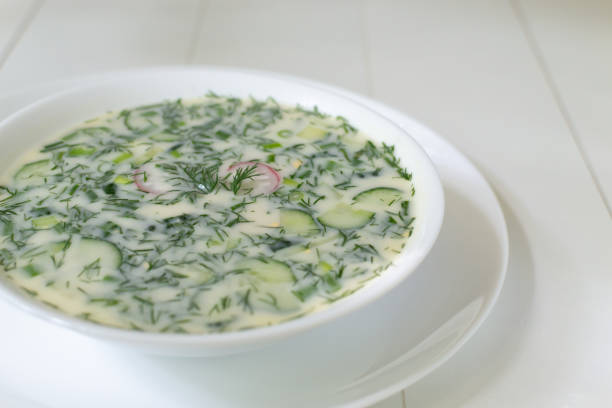 A bowl of chilled cucumber soup garnished with fresh dill and radish slices