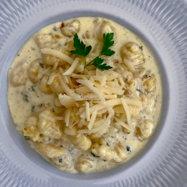 A delicious bowl of creamy pasta topped with shredded cheese and garnished with parsley.