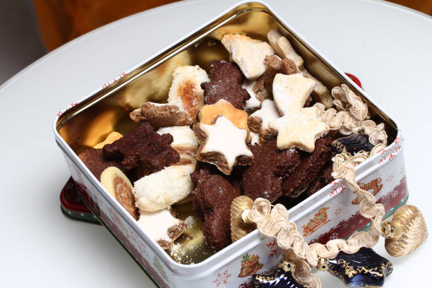 A festive tin filled with assorted Christmas cookies, including star shapes and other decorative designs.