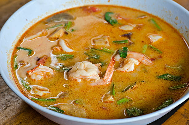 A bowl of spicy shrimp soup with vegetables