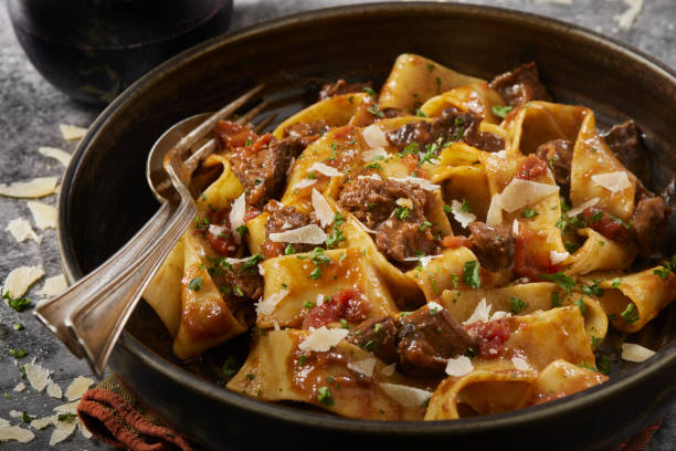 A bowl of pappardelle pasta with beef ragu and grated cheese