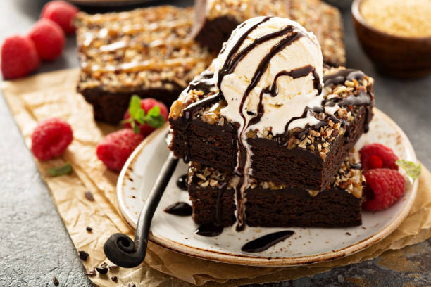 Delicious chocolate brownies topped with vanilla ice cream and chocolate sauce, served with fresh raspberries.