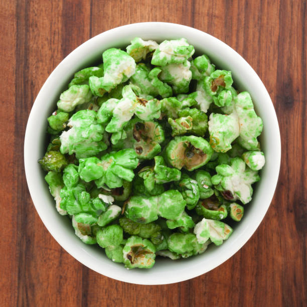 A bowl of green popcorn on a wooden table.