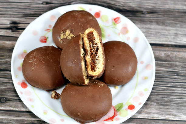 A plate of chocolate-covered cookies with one cookie cut in half, revealing its filling.