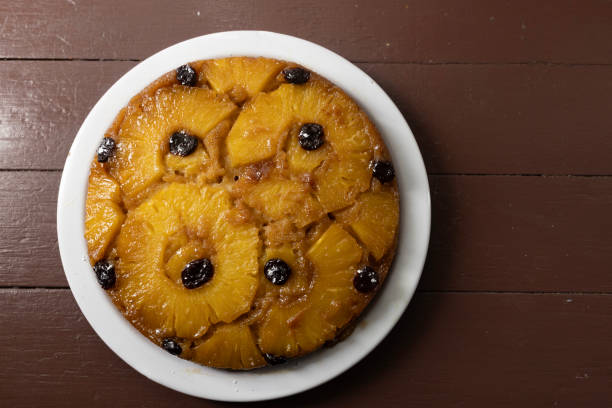 A delicious pineapple upside-down cake with caramelized pineapple slices and cherries, presented on a white plate.