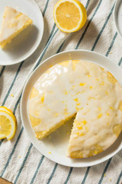 A delicious lemon cake with a shiny glaze, sliced and garnished with lemon slices.