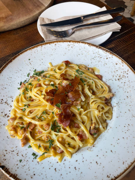 A plate of creamy pasta topped with crispy bacon and herbs