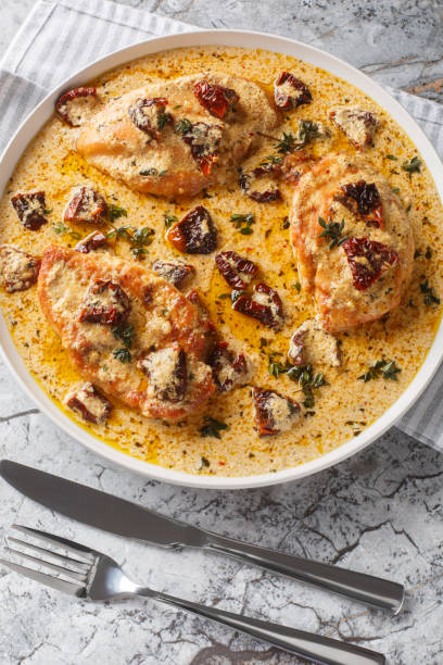 Creamy chicken dish with sun-dried tomatoes and herbs served in a white bowl