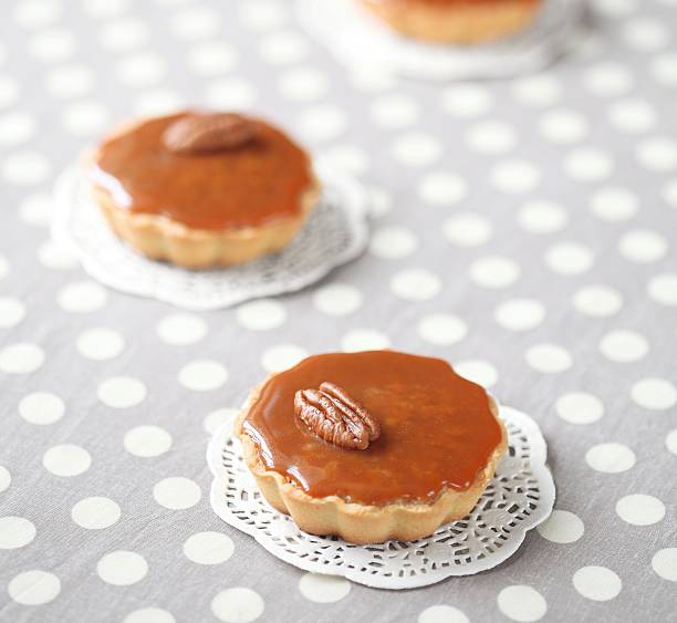 Close-up of pecan tarts on lace doilies against a polka dot background