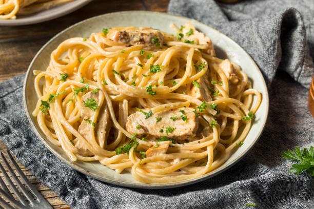 A plate of creamy pasta with chicken and parsley garnishing