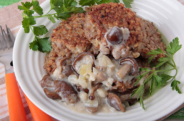 A plate of meat patties served with a creamy mushroom sauce and garnished with fresh parsley.