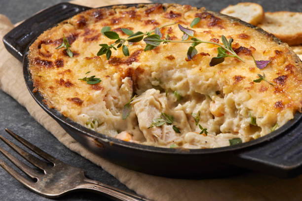 A delicious creamy chicken casserole topped with golden brown crust in a black dish, served with slices of bread.