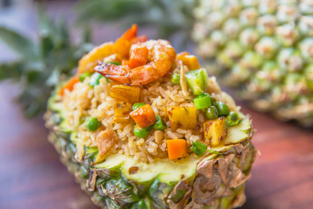 A vibrant dish of fried rice served in a pineapple half, topped with shrimp and colorful vegetables.