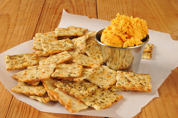 A plate of seasoned crackers served with a small bowl of orange cheese spread