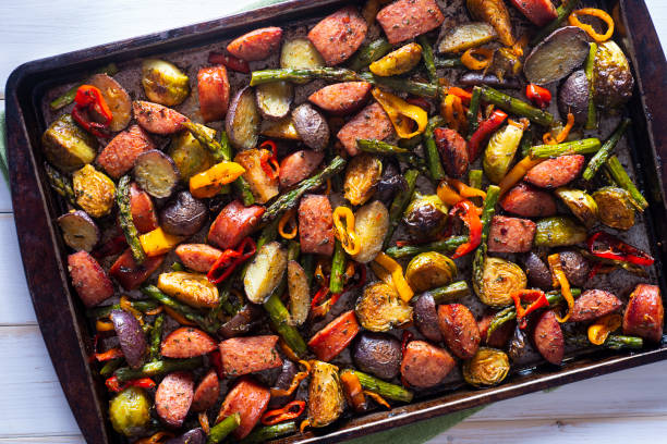 A colorful assortment of roasted vegetables and sausage on a baking tray.