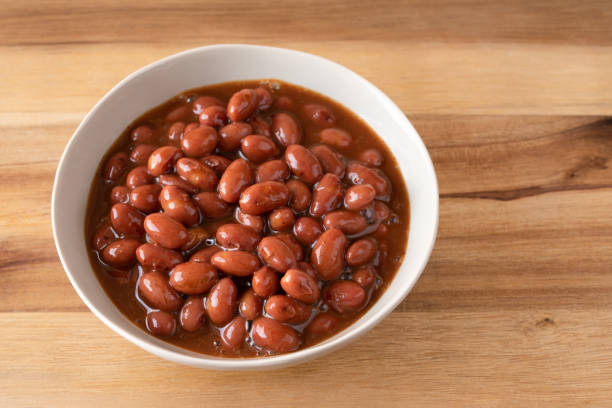 A bowl of cooked red kidney beans in a rich broth on a wooden surface