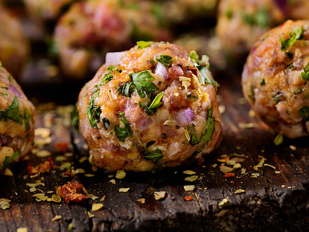 Close-up of meatballs garnished with herbs and spices on a wooden surface.