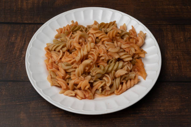 A plate of colorful fusilli pasta with a mix of red and green sauces, served on a white plate.