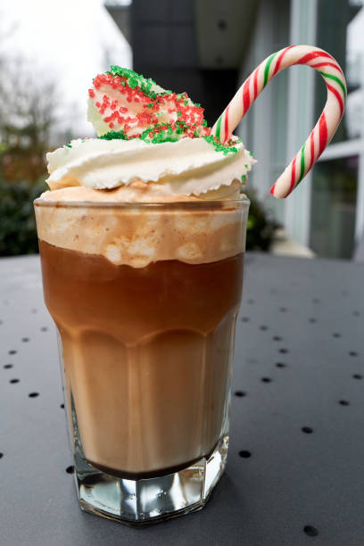 A festive layered coffee drink topped with whipped cream, candy cane, and holiday sprinkles.