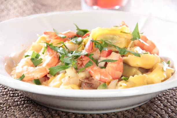 A plate of pasta with shrimp and vegetables garnished with fresh parsley