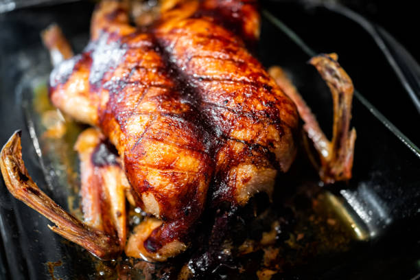 A perfectly roasted duck with crispy skin, displayed in a glass baking dish.