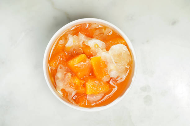 A bowl of colorful fruit salad with chunks of mango and coconut in a sweet syrup.