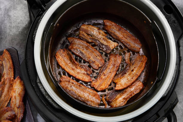 Cooked pork belly slices in an air fryer basket.